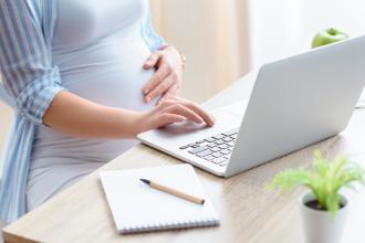 Pregnant woman working on coomputer.