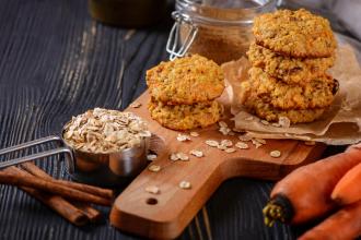 Carrot cookies stacked on cutting board.