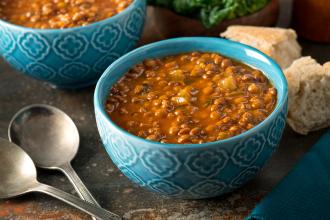 Curried lentil soup in blue bowl with spoons and bread on the sides