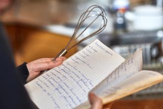 Person reading a handwritten recipe book. 