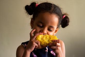 Girl eating corn on the cob.