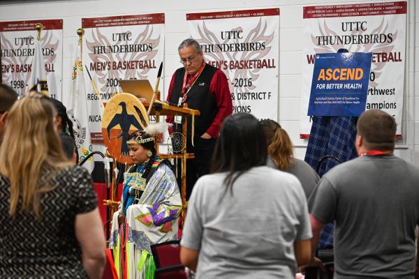 Community members standing during the traditional songs and prayers before the community  engagement event. 