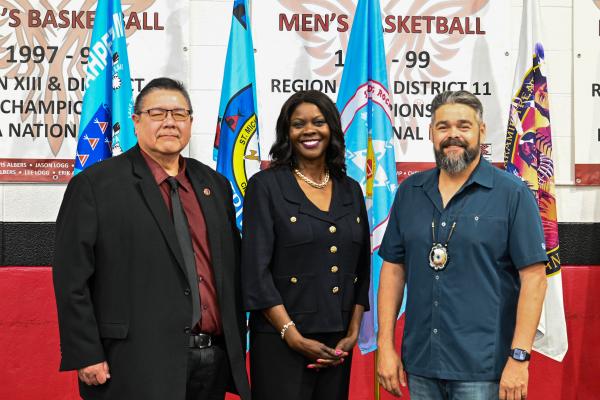  Dr. Leander R. McDonald, President of United Tribes Technical College (UTTC), Dr. Chavonda Jacobs-Young, USDA Under Secretary for Research, Education, and Economics and USDA Chief Scientist, and  Chairman Jamie Azure, Turtle Mountain Band of Chippewa Indians and Chairman of the Board for UTTC,  standing together and smiling. 