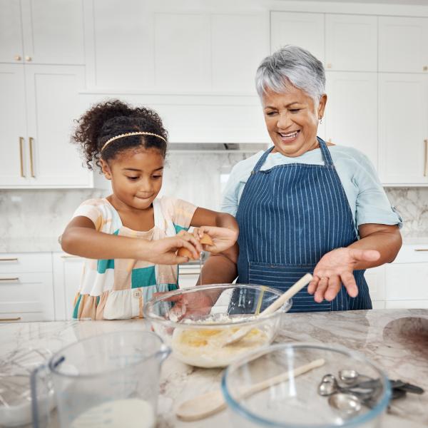 Grandmother and granddaughter mixing a cake.